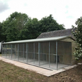 Load image into Gallery viewer, A multi-unit wooden dog kennel block with multiple runs. The structure is built with pressure-treated timber and features galvanized steel bar panels for the runs, with each unit having a separate, enclosed sleeping area. The kennel is designed for multiple dogs and is durable and secure.