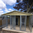 Load image into Gallery viewer, A multi-unit wooden dog kennel block with multiple runs. The structure is built with pressure-treated timber and features galvanized steel bar panels for the runs, with each unit having a separate, enclosed sleeping area. The kennel is designed for multiple dogs and is durable and secure.