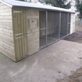 Load image into Gallery viewer, KENNELSTORE Wymbury Double Wooden Dog Kennel, a 21ft x 5ft multi-dog housing unit. The kennel features a distinctive apex roof and is made from pressure-treated tanalised timber, with two separate runs equipped with galvanised panels for security.