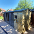 Load image into Gallery viewer, KENNELSTORE Wymbury Double Wooden Dog Kennel, a 14ft x 5ft multi-dog housing unit. The kennel features a distinctive apex roof and is made from pressure-treated tanalised timber, with two separate runs equipped with galvanised panels for security.
