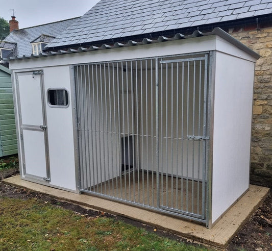 Thermal dog kennel with insulated white walls, metal bar front gate, and side access door with window