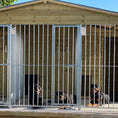 Load image into Gallery viewer, A multi-unit wooden dog kennel block with multiple runs. The structure is built with pressure-treated timber and features galvanized steel bar panels for the runs, with each unit having a separate, enclosed sleeping area. The kennel is designed for multiple dogs and is durable and secure.
