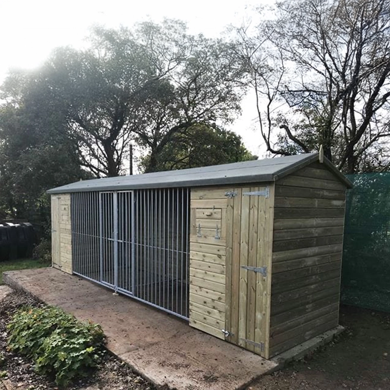 KENNELSTORE Wymbury Double Wooden Dog Kennel, a 18ft x 5ft multi-dog housing unit. The kennel features a distinctive apex roof and is made from pressure-treated tanalised timber, with two separate runs equipped with galvanised panels for security.
