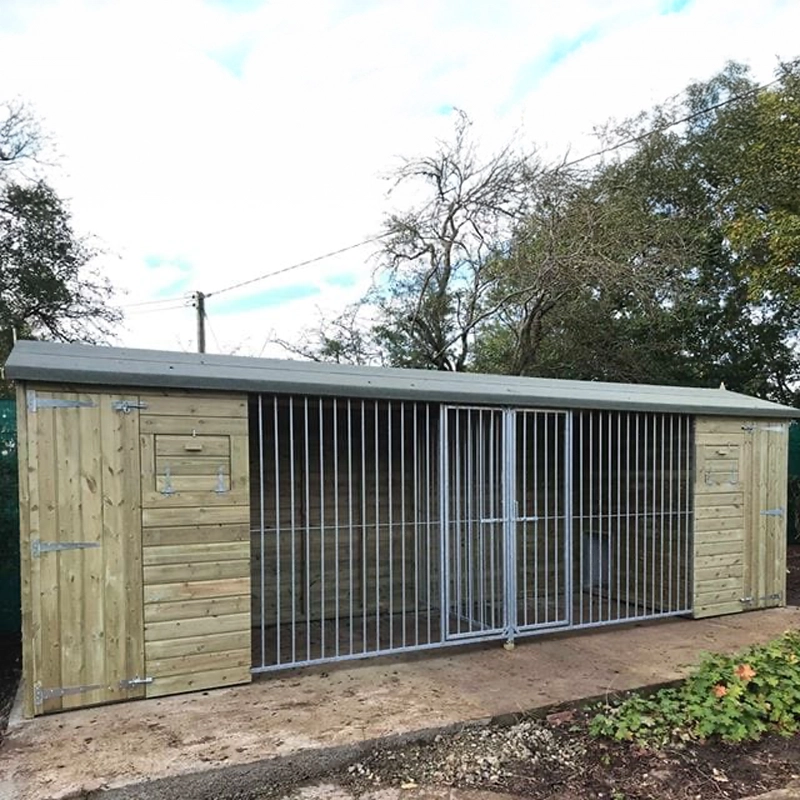 KENNELSTORE Wymbury Double Wooden Dog Kennel, a 21ft x 5ft multi-dog housing unit. The kennel features a distinctive apex roof and is made from pressure-treated tanalised timber, with two separate runs equipped with galvanised panels for security.