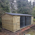 Load image into Gallery viewer, KENNELSTORE Wymbury Double Wooden Dog Kennel, a 21ft x 5ft multi-dog housing unit. The kennel features a distinctive apex roof and is made from pressure-treated tanalised timber, with two separate runs equipped with galvanised panels for security.
